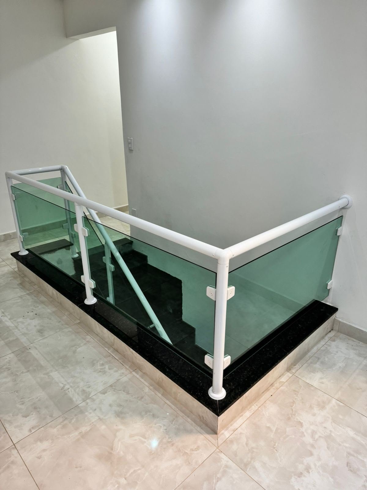 Guarda-corpo de vidro verde com corrimão branco